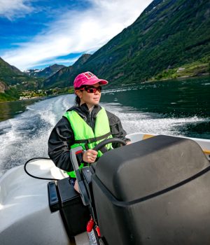 Woman driving a motor boat. Geiranger fjord, Beautiful Nature Norway.Summer vacation. Geiranger Fjord, a UNESCO World Heritage Site.
